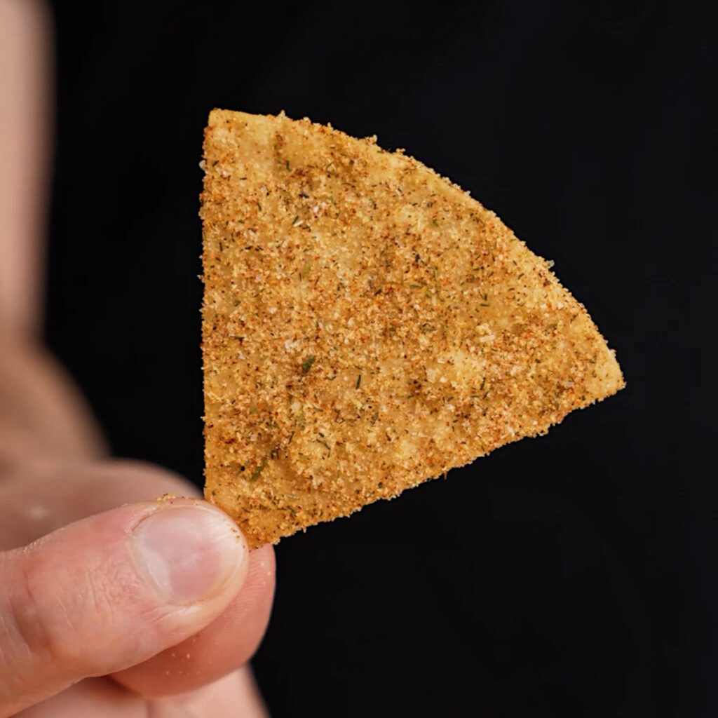 A detailed close-up of the red, green, and white seasoning dust on fried corn chips.