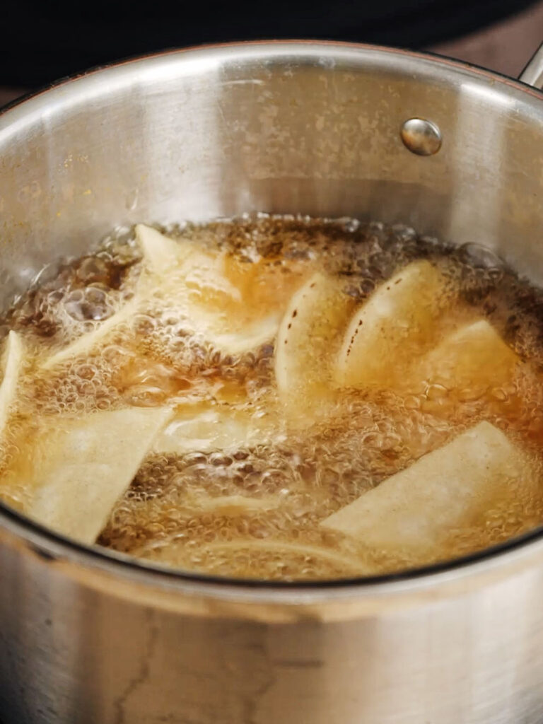 Tortilla chips for the homemade Cool Ranch Doritos recipe frying in a pot of oil.