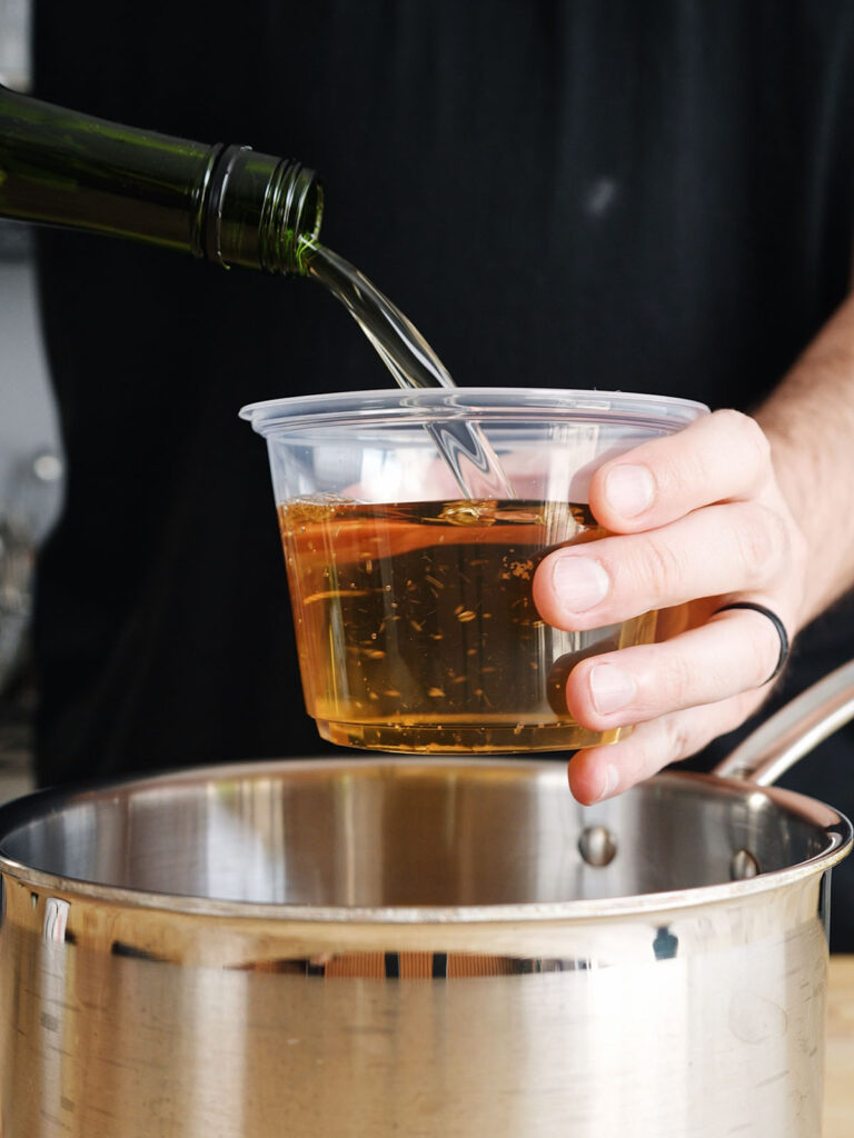 Pouring mirin into a measuring cup to create the sweet and savory tare glaze base for a homemade yakitori recipe.