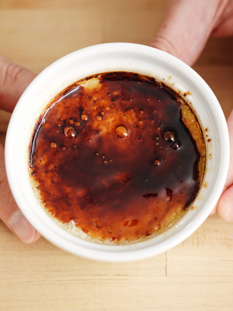 A top-down view of a perfectly caramelized, deep amber glass sugar crust on a freshly torched homemade creme brulee.