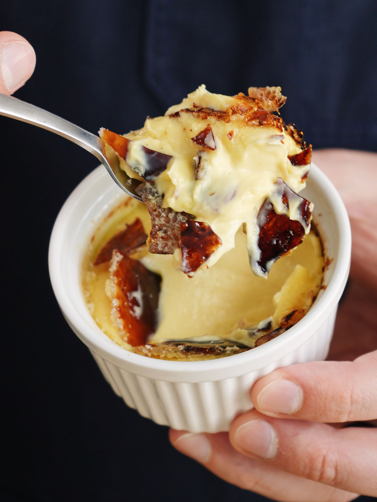 A spoonful of creamy homemade creme brulee showing the beautiful contrast of the shattered, caramelized sugar crust.