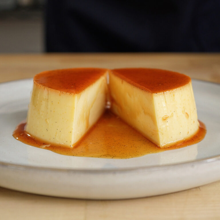A knife slicing directly through the center of a perfectly set, silky homemade flan.