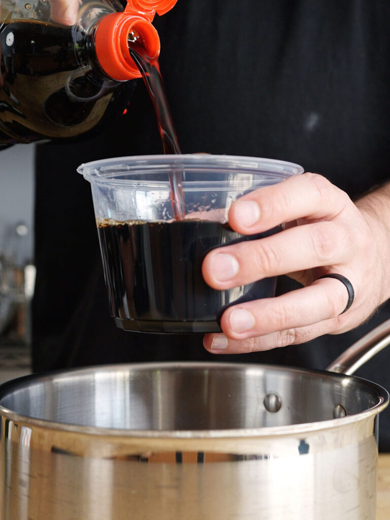 Measuring dark soy sauce to mix with mirin and brown sugar, completing the three-ingredient tare sauce for homemade yakitori.
