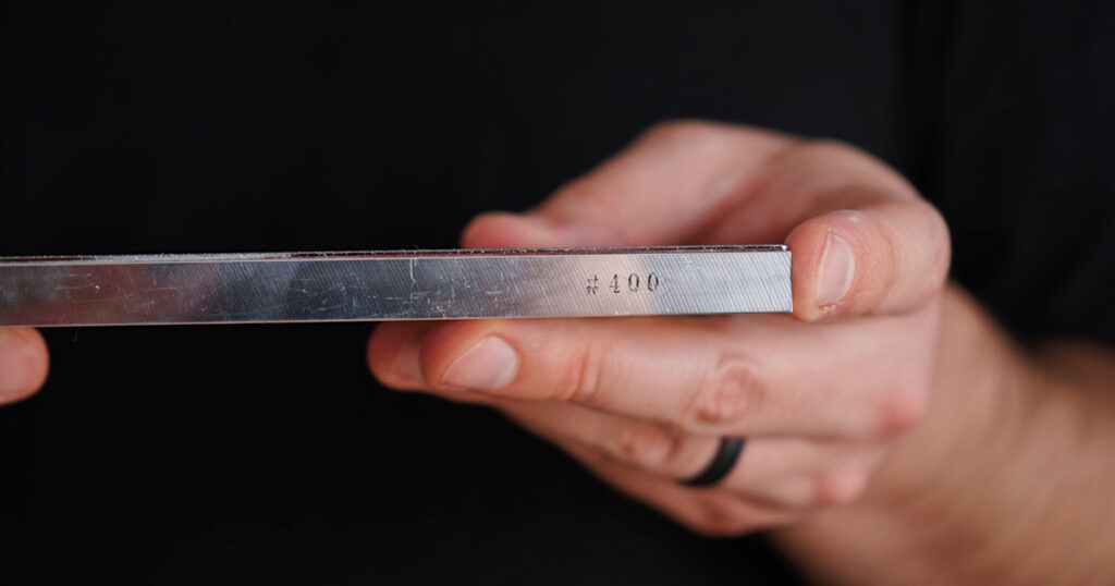 Hands holding a #400 grit diamond flattening steel for whetstone maintenance