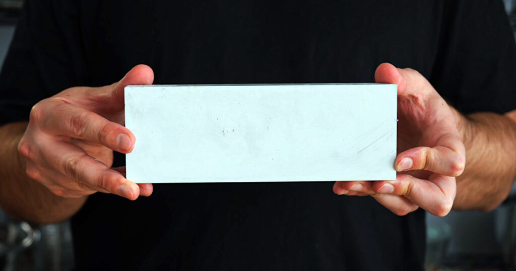 Hands holding a 5000-grit whetstone for refining a culinary blade's edge
