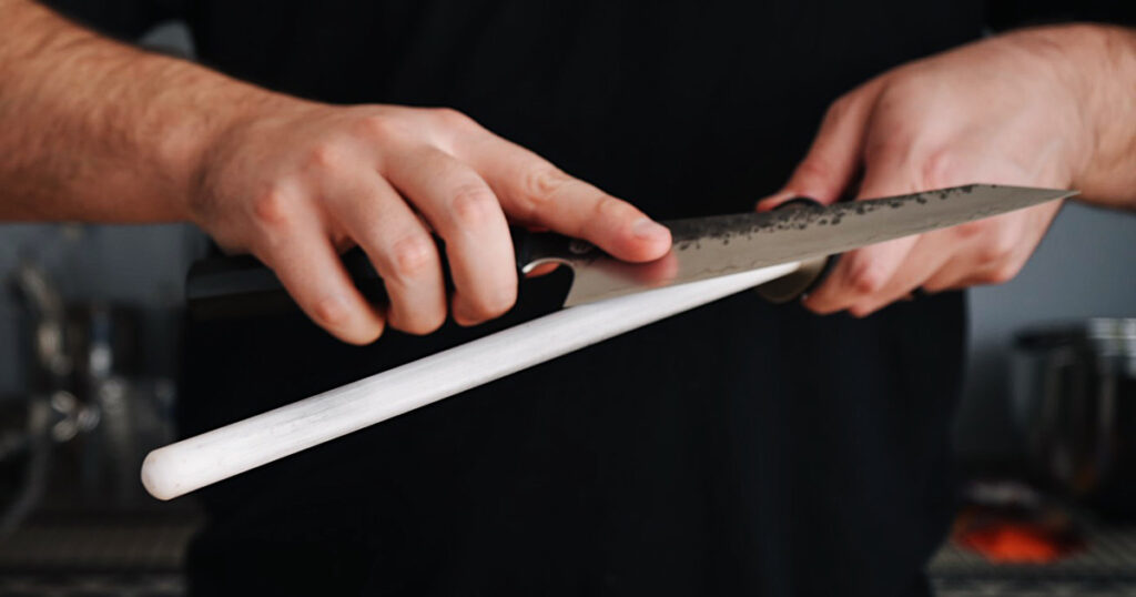 Cook using a white ceramic honing rod on a knife