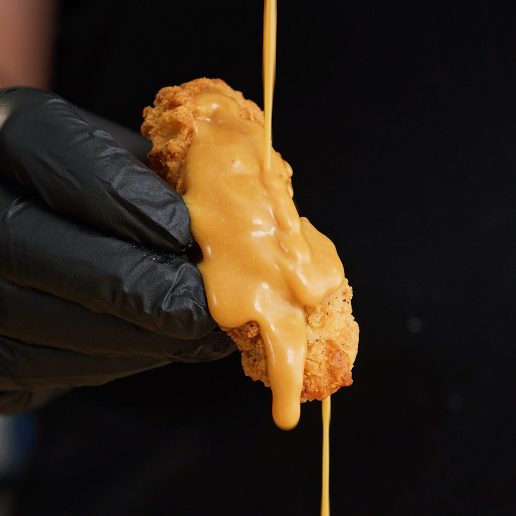 Drizzling sweet and tangy homemade Chick-fil-A sauce over a crispy piece of fried chicken