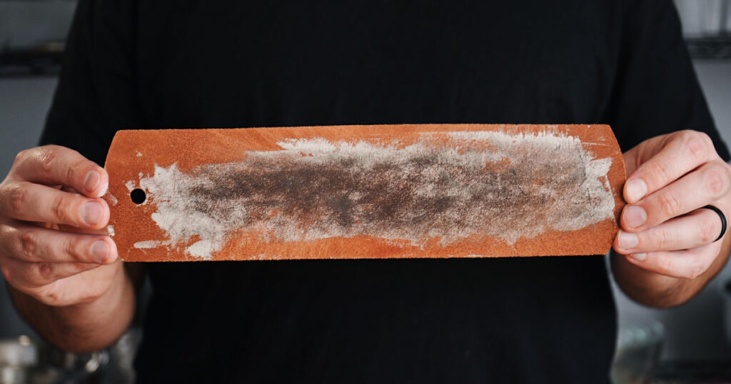 Hands holding a leather strop with diamond compound for knife sharpening