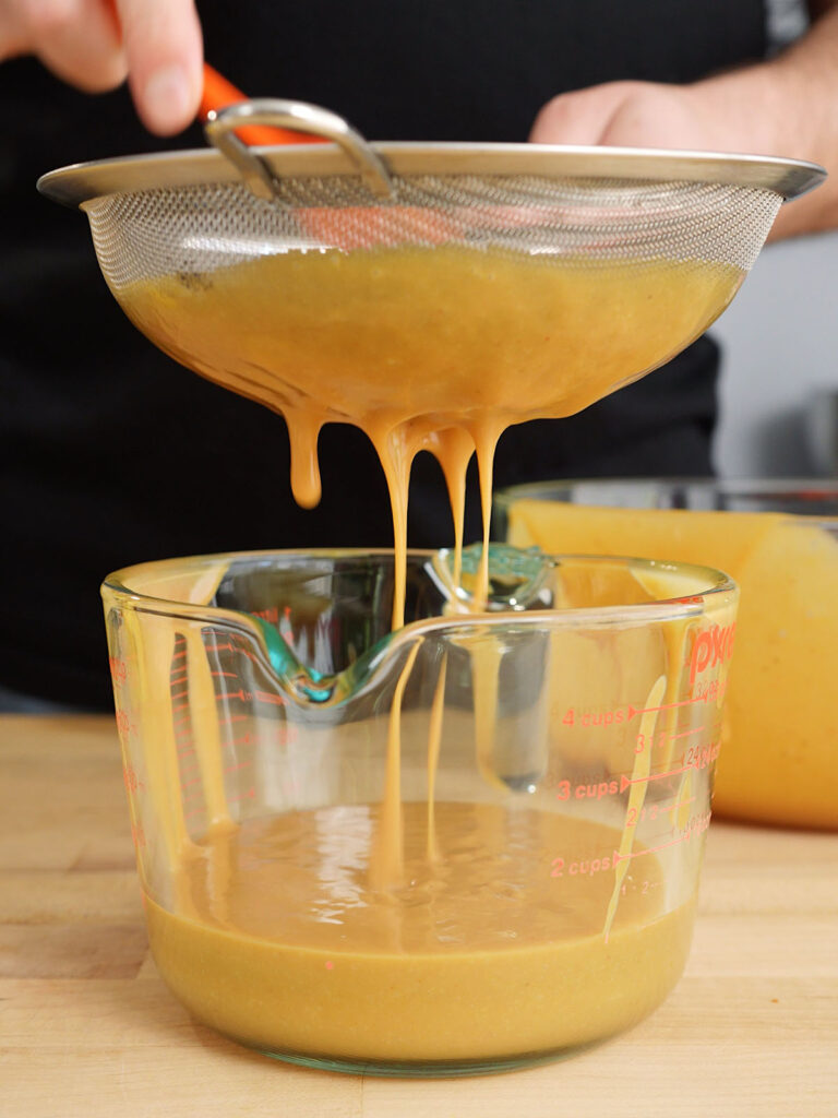Straining homemade Chick-fil-A sauce through a fine-mesh sieve for a perfectly smooth, restaurant-quality texture.